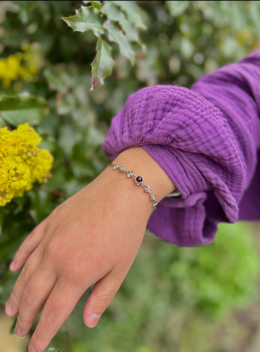 Lifestyle foto van een zilveren gepersonaliseerde fotoarmband, gedragen bij een paarse blouse in een natuurlijke omgeving.
