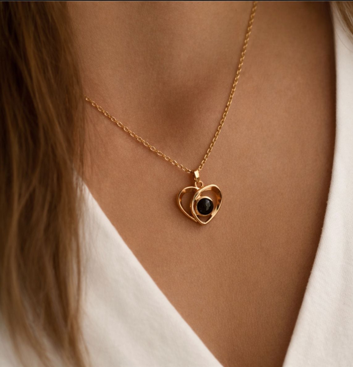 Gedetailleerde foto van de gepersonaliseerde hartvormige fotoketting in het roségoud gedragen door een model.