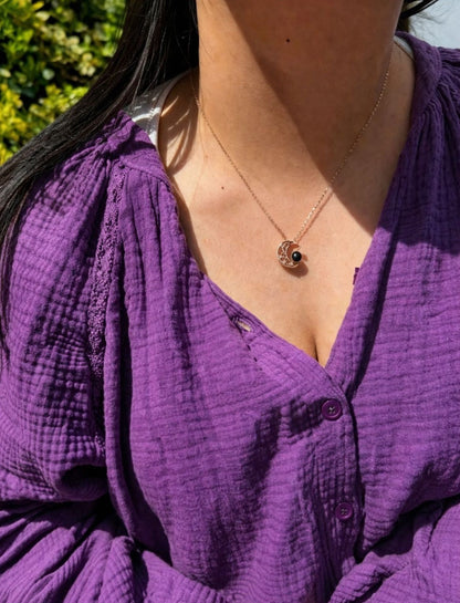 Lifestyle foto van een gepersonaliseerde maanvormige fotoketting, gedragen bij een paarse blouse.